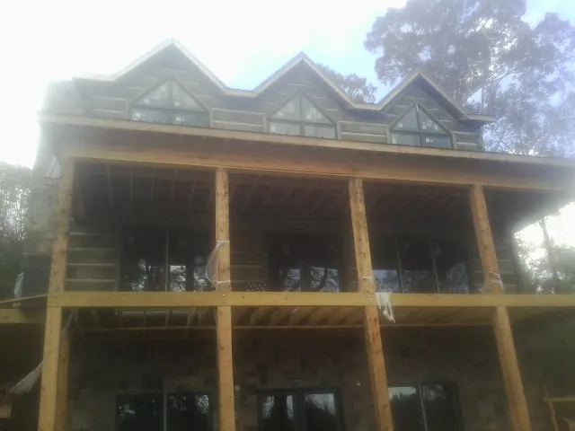 Dormers and porch framing on a large log home under construction — Roof Coating work by our crew in Cherry Valley